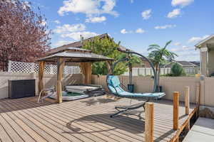 Deck with a fenced backyard, a gazebo, and a covered hot tub