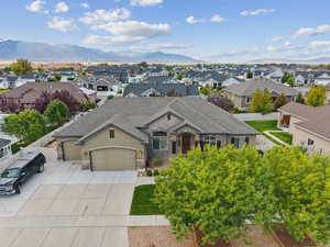 View of front of property with stone siding, concrete driveway, a garage, a mountain view, and roof with shingles