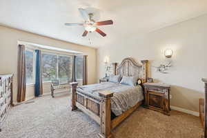 Carpeted bedroom with a ceiling fan and baseboards