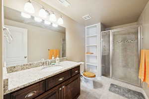 Full bath with vanity, a stall shower, and light tile patterned floors