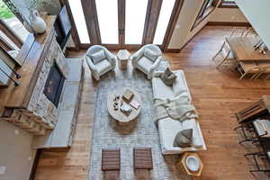 Living room featuring light wood finished floors, a stone fireplace, and healthy amount of natural light