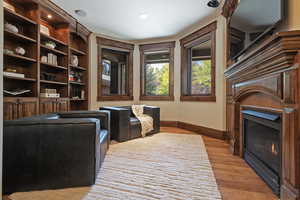 Living area featuring light wood-style floors, a glass covered fireplace, and recessed lighting