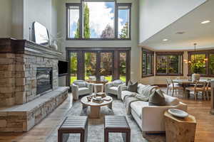 Living room featuring light wood-style floors, a fireplace, a high ceiling, recessed lighting, and french doors