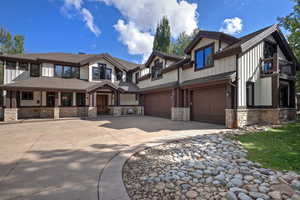 View of front of home with stone siding, concrete driveway, roof with shingles, and an attached garage