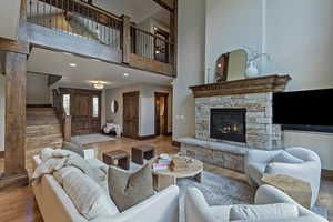 Living room featuring stairs, wood finished floors, a fireplace, a towering ceiling, and recessed lighting