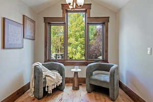 Living area with wood finished floors, a chandelier, and vaulted ceiling
