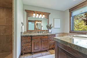 Full bath featuring two vanities, tile walls, and a tile shower