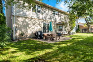 Rear view of house featuring a lawn, a patio, and brick /siding