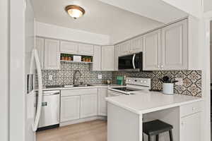 Kitchen featuring a peninsula/breakfast bar area, decorative backsplash, and light wood-style floors