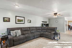 Living area featuring carpet, a textured ceiling, and a ceiling fan