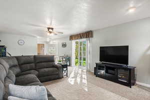 Living area featuring carpet flooring, a textured ceiling, and ceiling fan