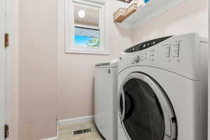 Laundry room with light wood-type flooring and washer and dryer