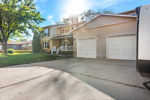 Traditional-style home featuring brick, stone, siding, concrete driveway, a porch, and 2 car garage