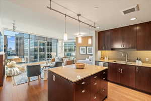 Kitchen with dark brown cabinetry, a kitchen island, backsplash, track lighting, and light wood-type flooring