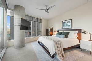 Carpeted bedroom with multiple windows and ceiling fan