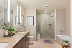 Full bath featuring a garden tub, tile walls, double vanity, a stall shower, and light tile patterned floors