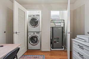 Laundry area featuring light wood-type flooring and stacked washer / drying machine