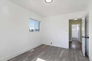 Unfurnished room featuring dark wood-style flooring and baseboards