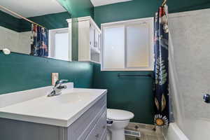 Bathroom featuring shower / tub combo, vanity, and a textured wall
