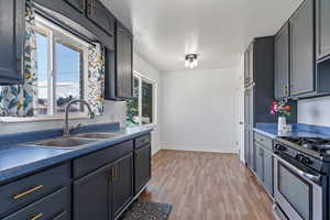 Kitchen featuring light wood-type flooring, gas range, dark countertops, and gray cabinets