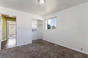 Unfurnished bedroom with dark carpet and a closet