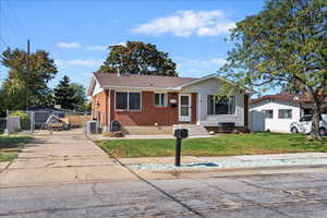 View of front facade with entry steps, brick siding, roof with shingles, and a gate