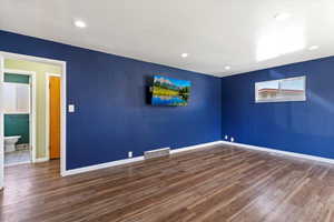 Empty room featuring dark wood-style floors and recessed lighting