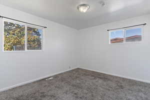 Carpeted spare room with baseboards and a smoke detector