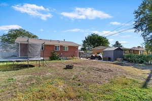 View of green lawn featuring a trampoline, a storage unit, and a patio