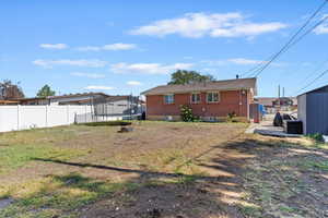 Back of property with a trampoline, a fenced backyard, and brick siding