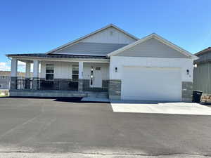 Craftsman inspired home featuring a porch, board and batten siding, stone siding, and concrete driveway