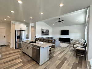 Kitchen featuring a textured ceiling, recessed lighting, light stone countertops, lofted ceiling, and appliances with stainless steel finishes