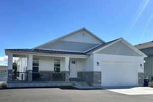 Craftsman-style home featuring board and batten siding, covered porch, a standing seam roof, and an attached garage