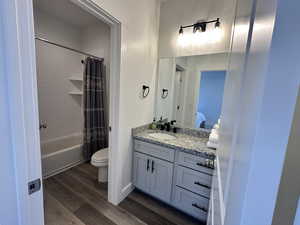 Ensuite bathroom featuring dark wood-style flooring, shower / bath combo, and vanity