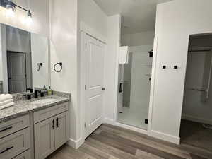 Full bath with a shower stall, vanity, light wood-style flooring, and a closet