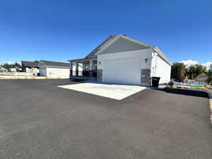 View of side of property featuring a porch, stone siding, driveway, a garage, and board and batten siding