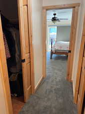 Hallway with dark colored carpet and baseboards