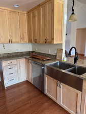 Kitchen featuring light brown cabinets, dark stone counters, dishwasher, and dark wood-style floors