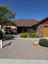 Ranch-style house featuring stone siding, an attached garage, and roof with shingles