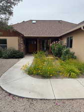 View of front of property with a shingled roof, stucco siding, and stone siding