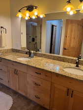 Bathroom featuring double vanity, a shower stall, and dark tile patterned floors