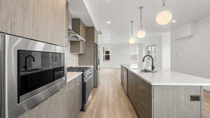 Images shown are of a similar completed unit. Kitchen with modern cabinets, appliances with stainless steel finishes, light wood finished floors, decorative backsplash, and a kitchen island with sink