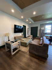 Living area with recessed lighting, a raised ceiling, dark wood-style flooring, and wooden ceiling