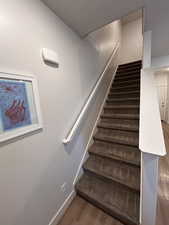 Staircase with wood finished floors and baseboards