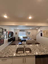 Kitchen featuring white cabinets, wood finished floors, light stone counters, open floor plan, and a textured ceiling