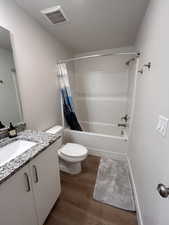 Full bath with shower / tub combo, vanity, and dark wood-type flooring