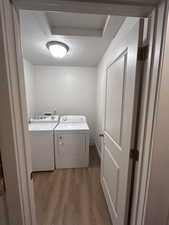 Washroom featuring a textured ceiling, wood finished floors, and separate washer and dryer