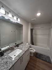 Full bathroom featuring shower / bath combination with curtain, dark wood finished floors, vanity, and a textured ceiling