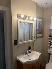 Full bath featuring a shower with curtain, vanity, decorative backsplash, and tile walls
