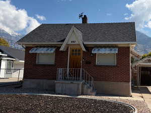 West-facing, bungalow-style house with a mountain view, roof with shingles, brick siding, and a chimney